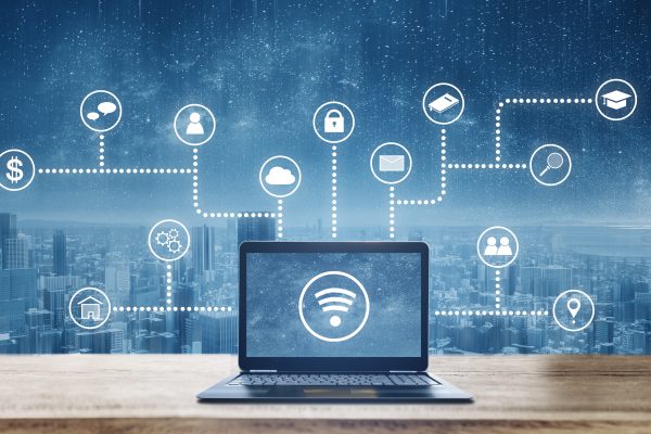 Computer laptop on wooden desk with wireless and application programming and social media icons. Internet networking and wireless technology
