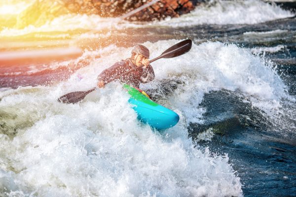 Guy in kayak sails mountain river. Whitewater kayaking, extreme sport rafting.